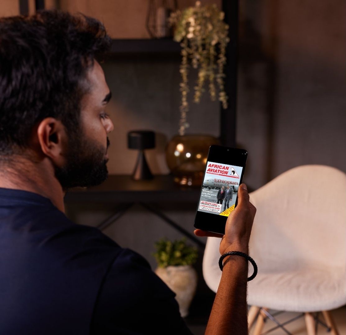 Man reading African Aviation magazine on smartphone at home.