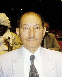 Prominent Political Figure at Conference Event Key subject seated in formal attire during a significant gathering.