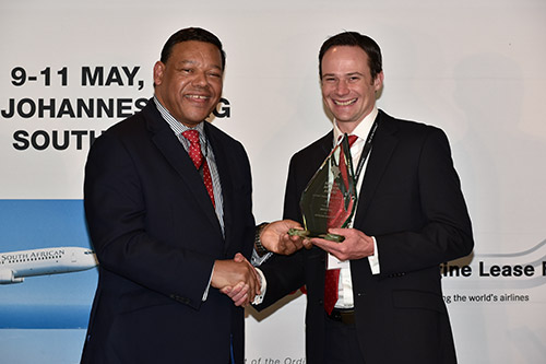 "Award Ceremony at South African Airlines Conference 2023" "Two men shake hands at an award ceremony in Johannesburg."
